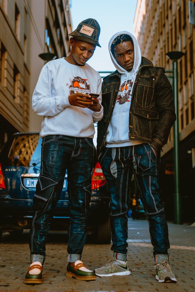 Young men in stylish denim outfits pose in the streets of Pretoria, South Africa.